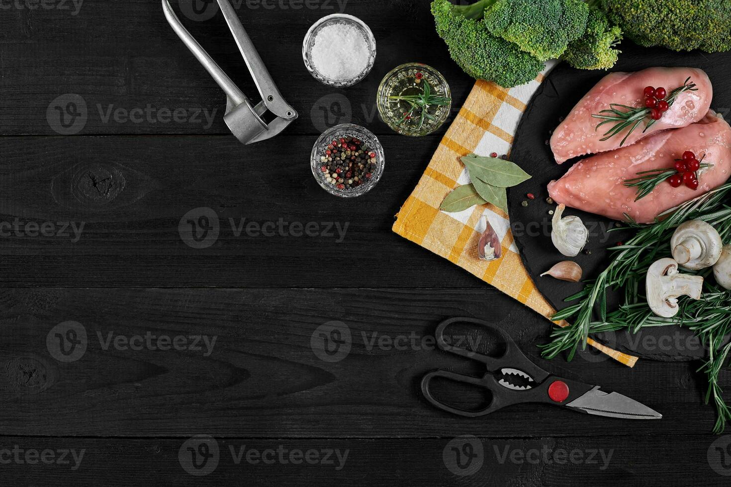 Cooking chicken breasts. On the table are spices - rosemary, red and black pepper, mushrooms, broccoli. Concept - healthy food. photo