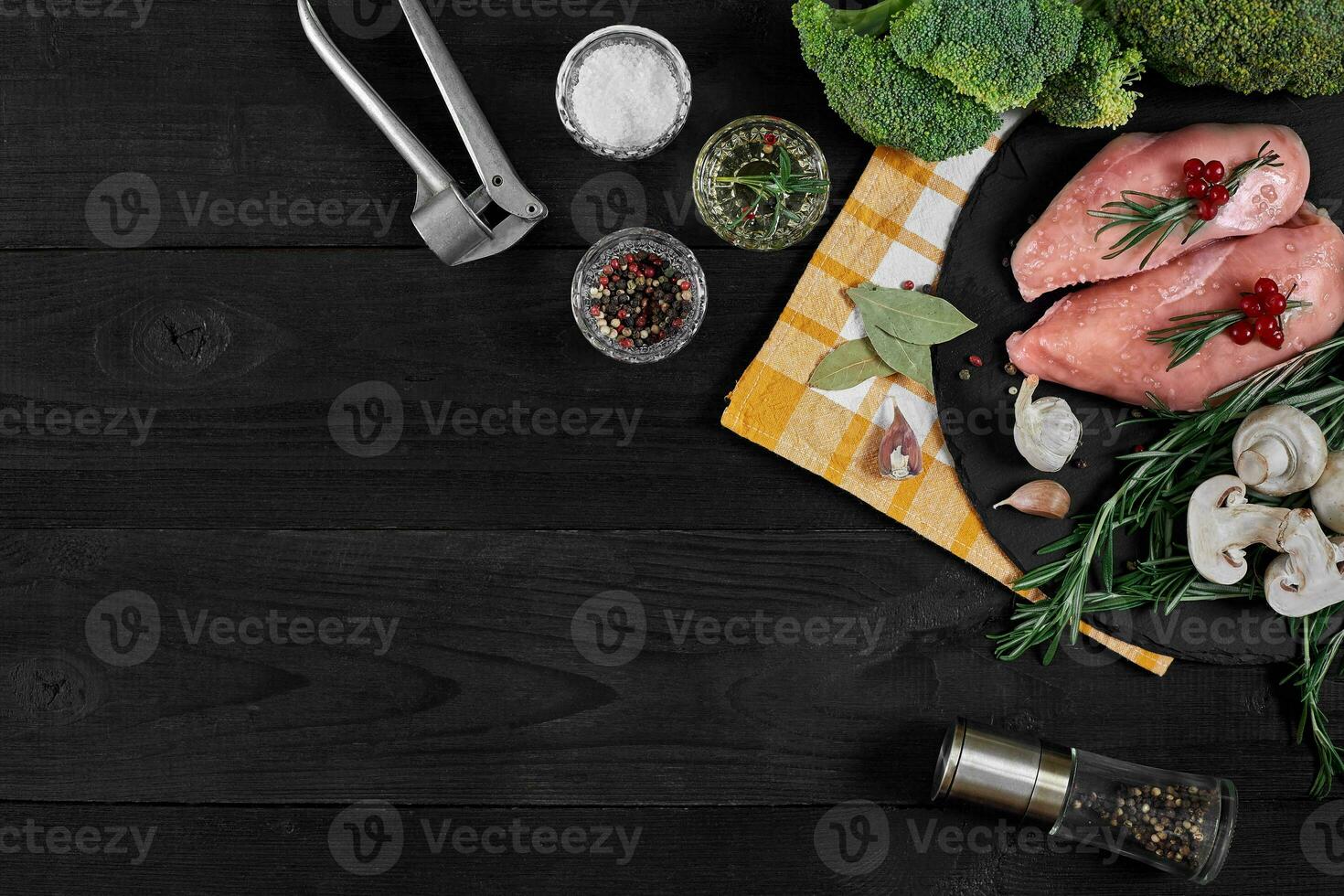 Cooking chicken breasts. On the table are spices - rosemary, red and black pepper, mushrooms, broccoli. Concept - healthy food. photo