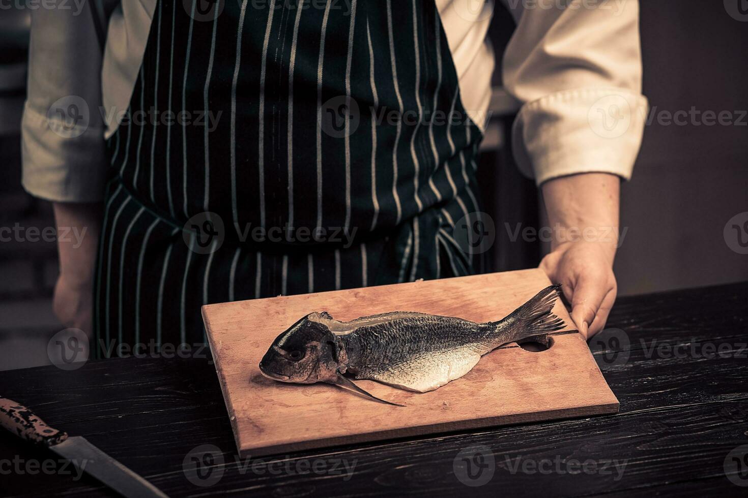 Chef cutting the fish on a board photo