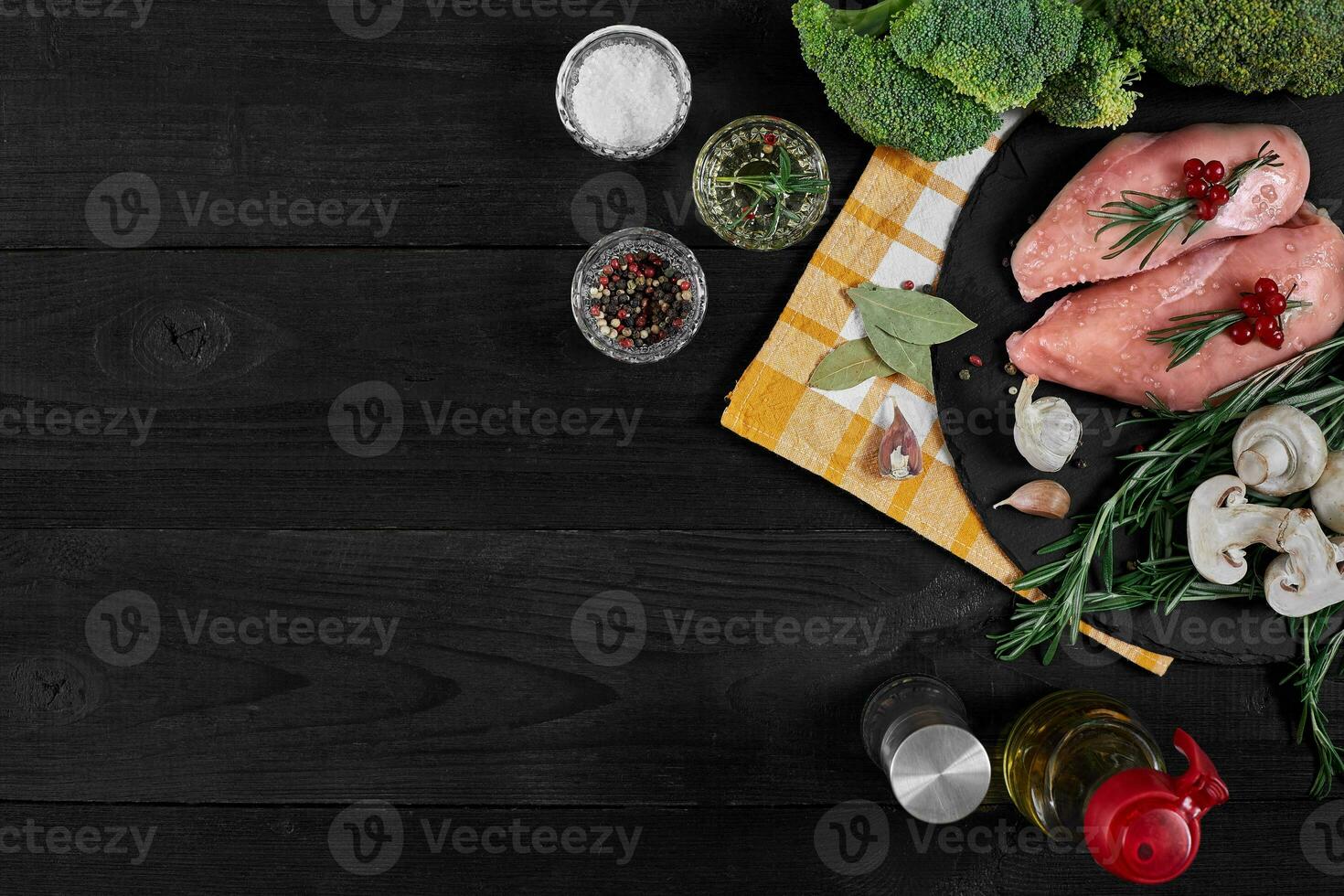 Cooking chicken breasts. On the table are spices - rosemary, red and black pepper, mushrooms, broccoli. Concept - healthy food. photo