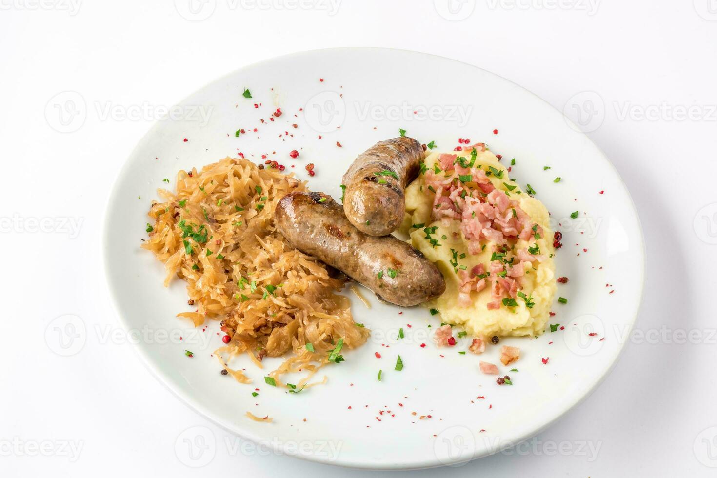 A la parrilla salchichas, patatas y cocido a fuego lento repollo en blanco plato de cerca ver desde arriba. foto