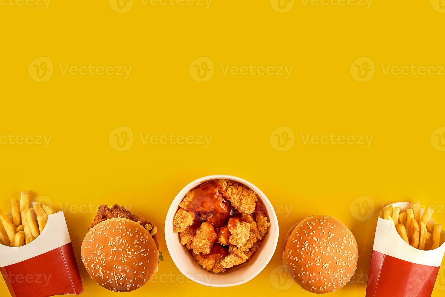 Fast food dish on yellow background. Fast food set fried chicken, meat burger and french fries. Take away fast food. photo