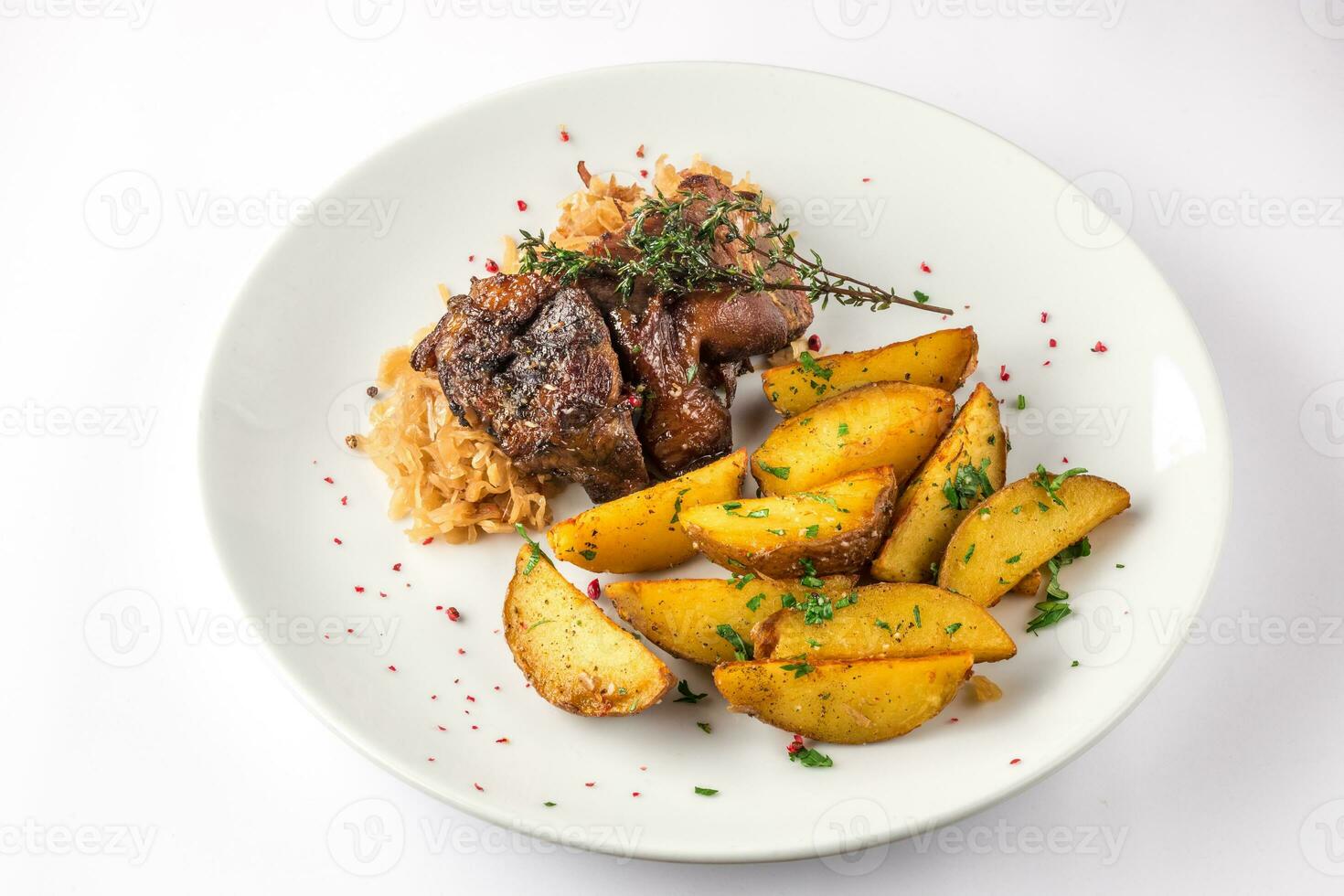 Pork knuckle with potatoes and cabbage on a white plate. Selective focus. photo