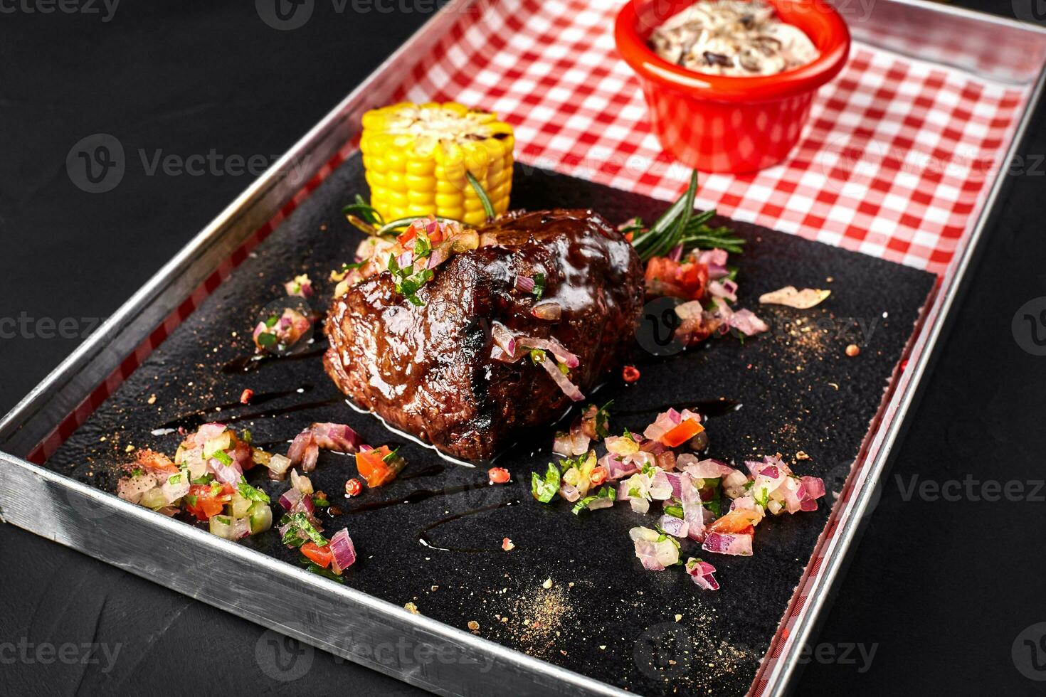 A piece of steak with salad, corn, mushrooms sauce on a blackboard photo