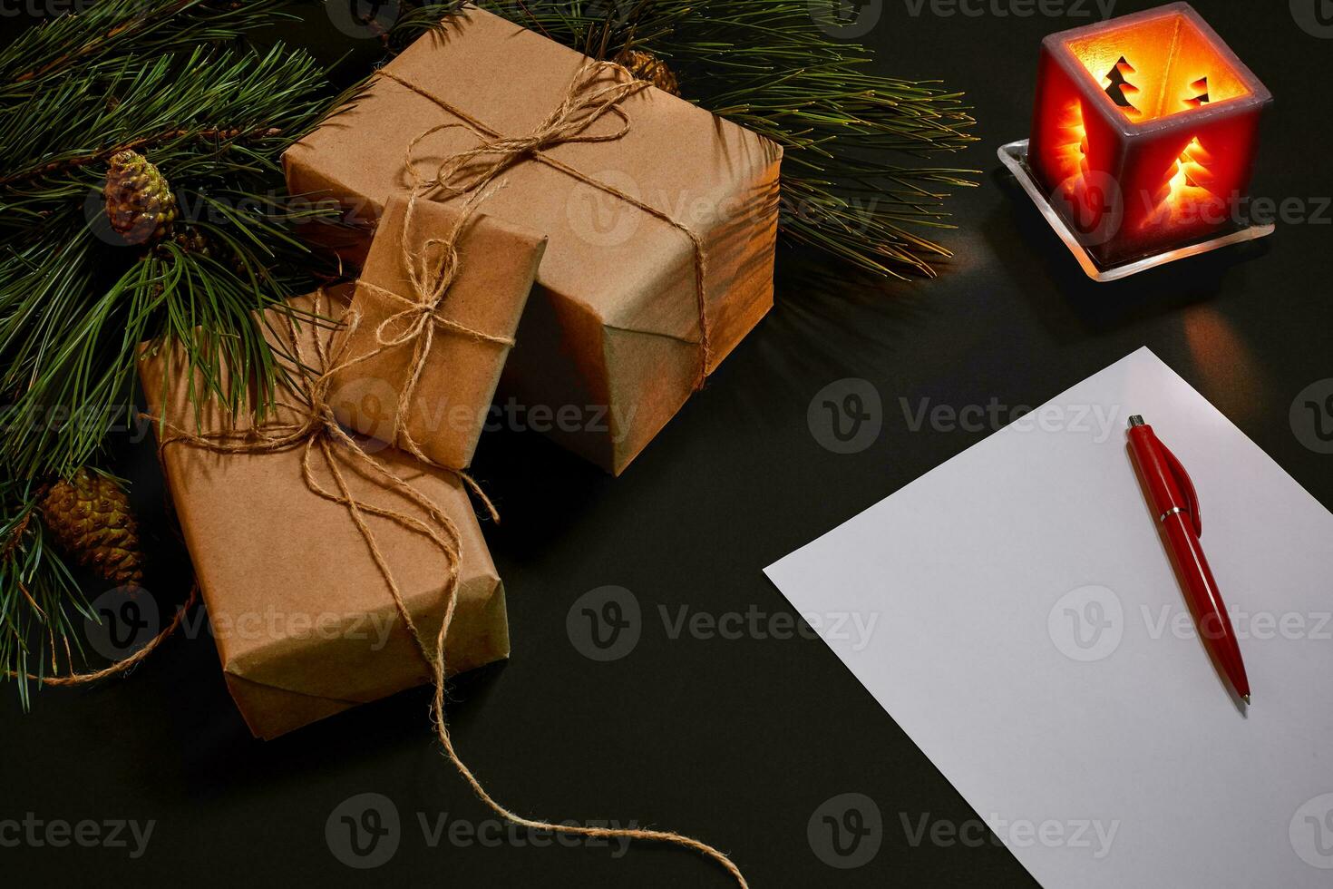 Christmas gifts and notebook lying near green spruce branch on black background top view. Space for text photo