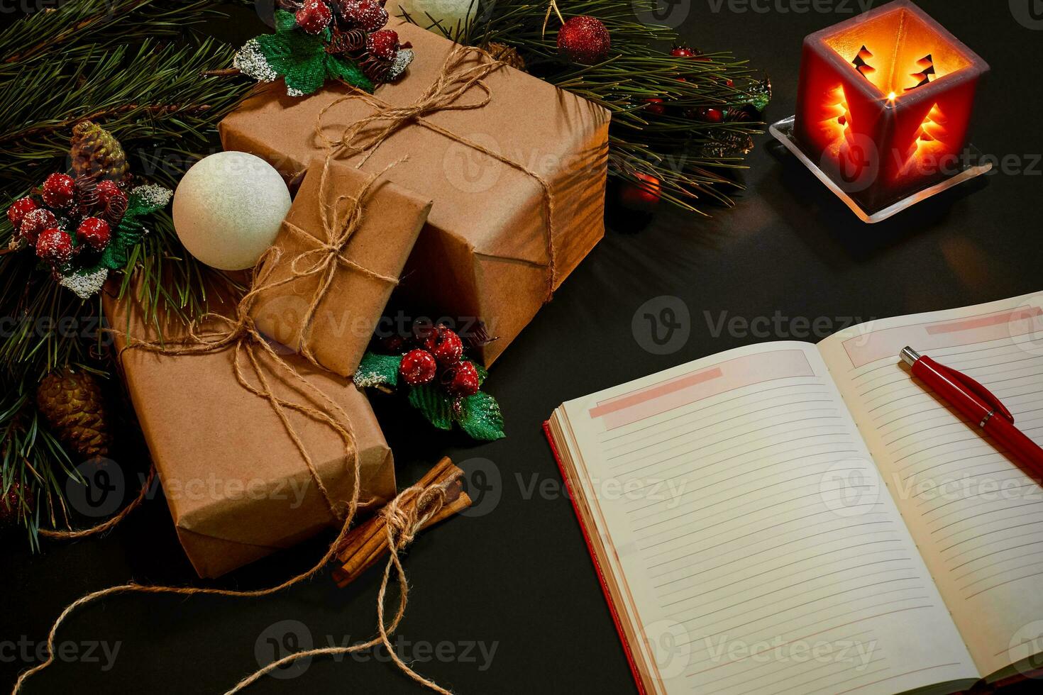 Christmas gifts and notebook lying near green spruce branch on black background top view. Space for text photo