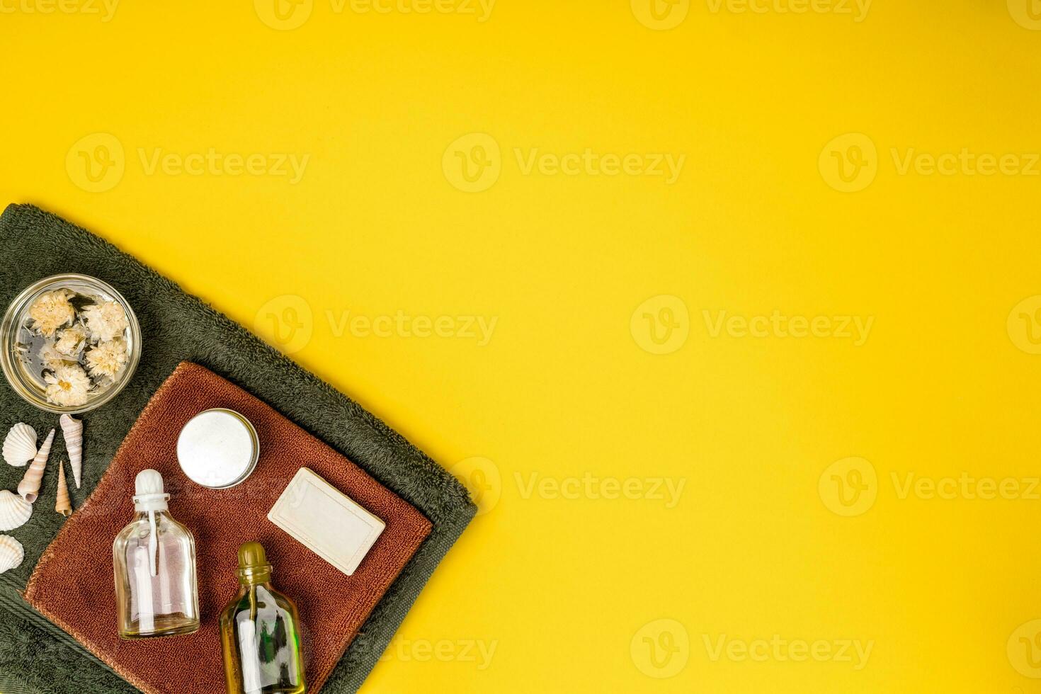 Spa or wellness setting in white colors. Bottles with essential aroma oil, towels, soap on yellow background. photo