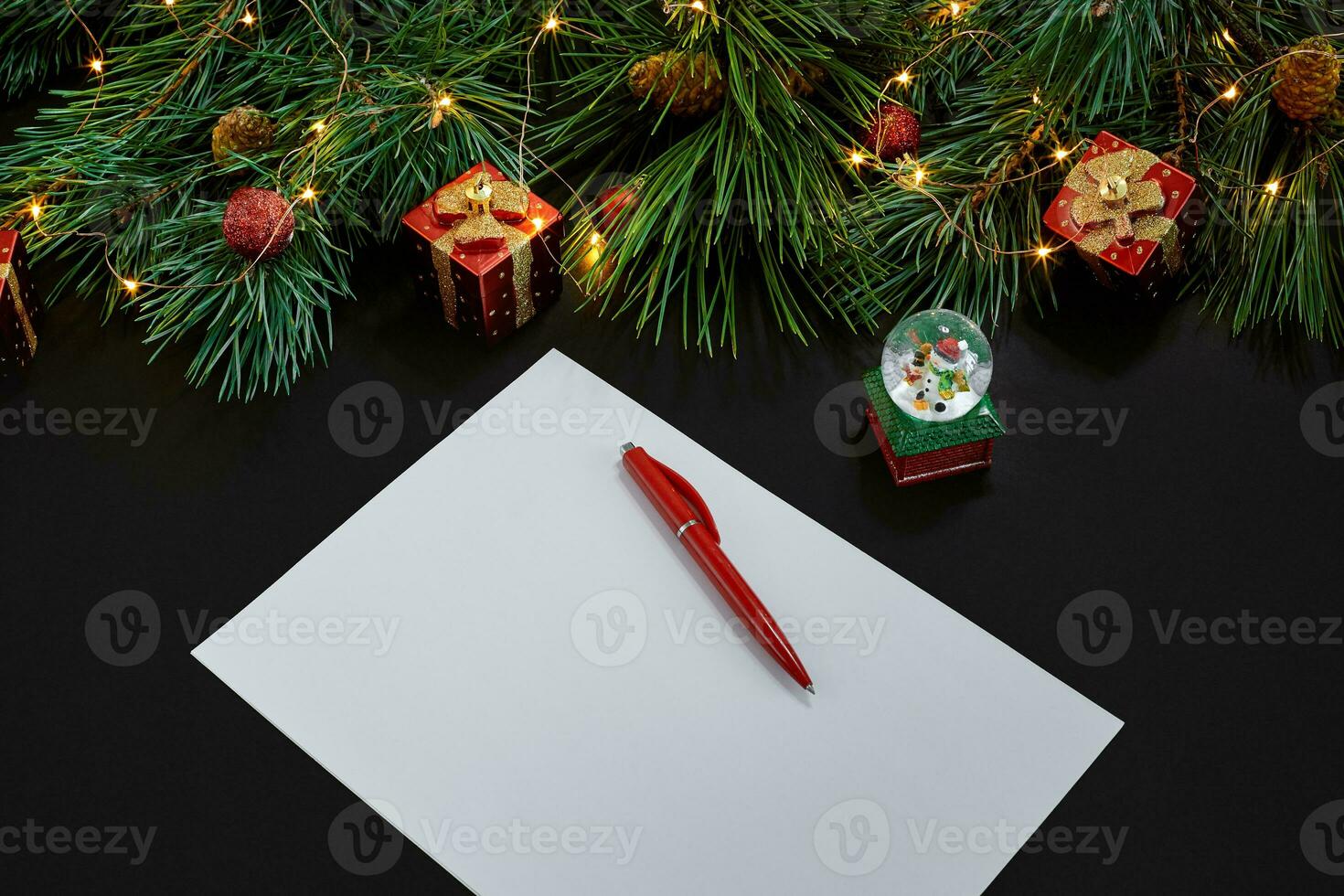 Christmas toys and notebook lying near green spruce branch on black background top view. Space for text photo
