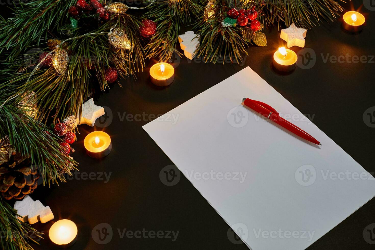 Red Christmas balls and notebook lying near green spruce branch on black background top view. Space for text photo