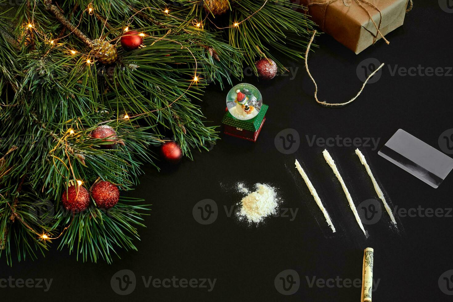 Cocaine divided into paths with Xmas toys and spruce branch on black background top view. photo