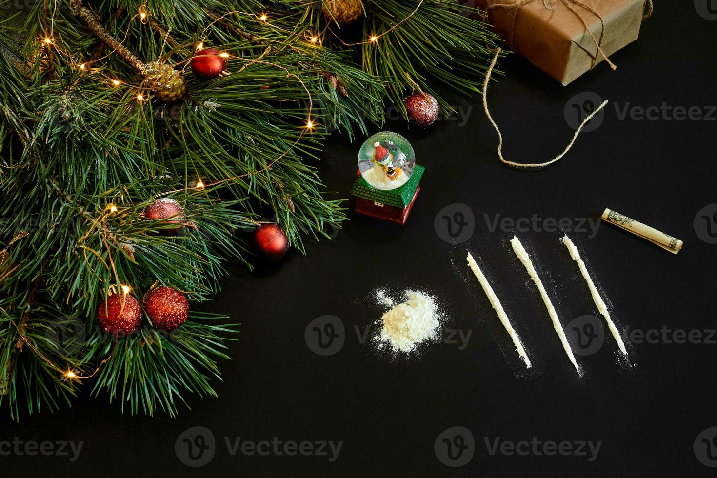 Cocaine divided into paths with Xmas toys and spruce branch on black background top view. photo