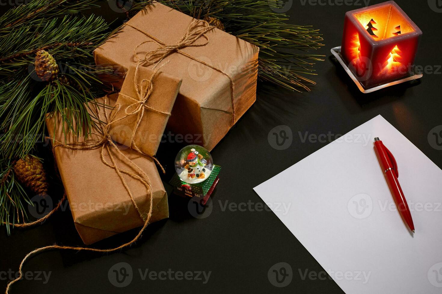Christmas gifts and notebook lying near green spruce branch on black background top view. Space for text photo