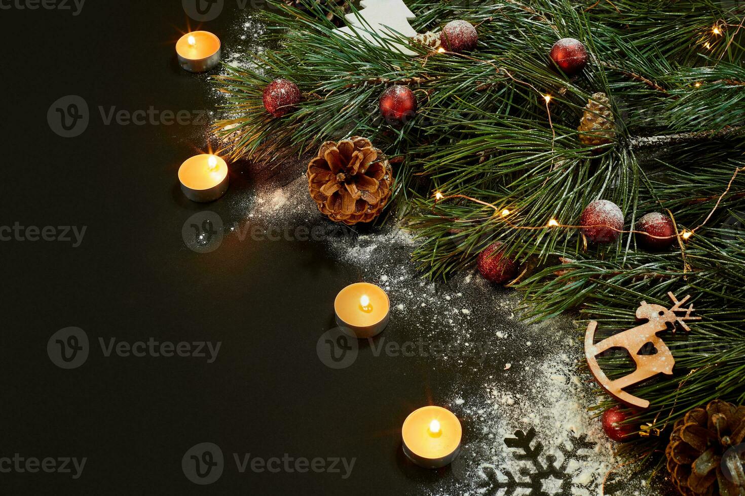 Christmas. Xmas toys, burning candles and spruce branch on black background top view. Space for text photo