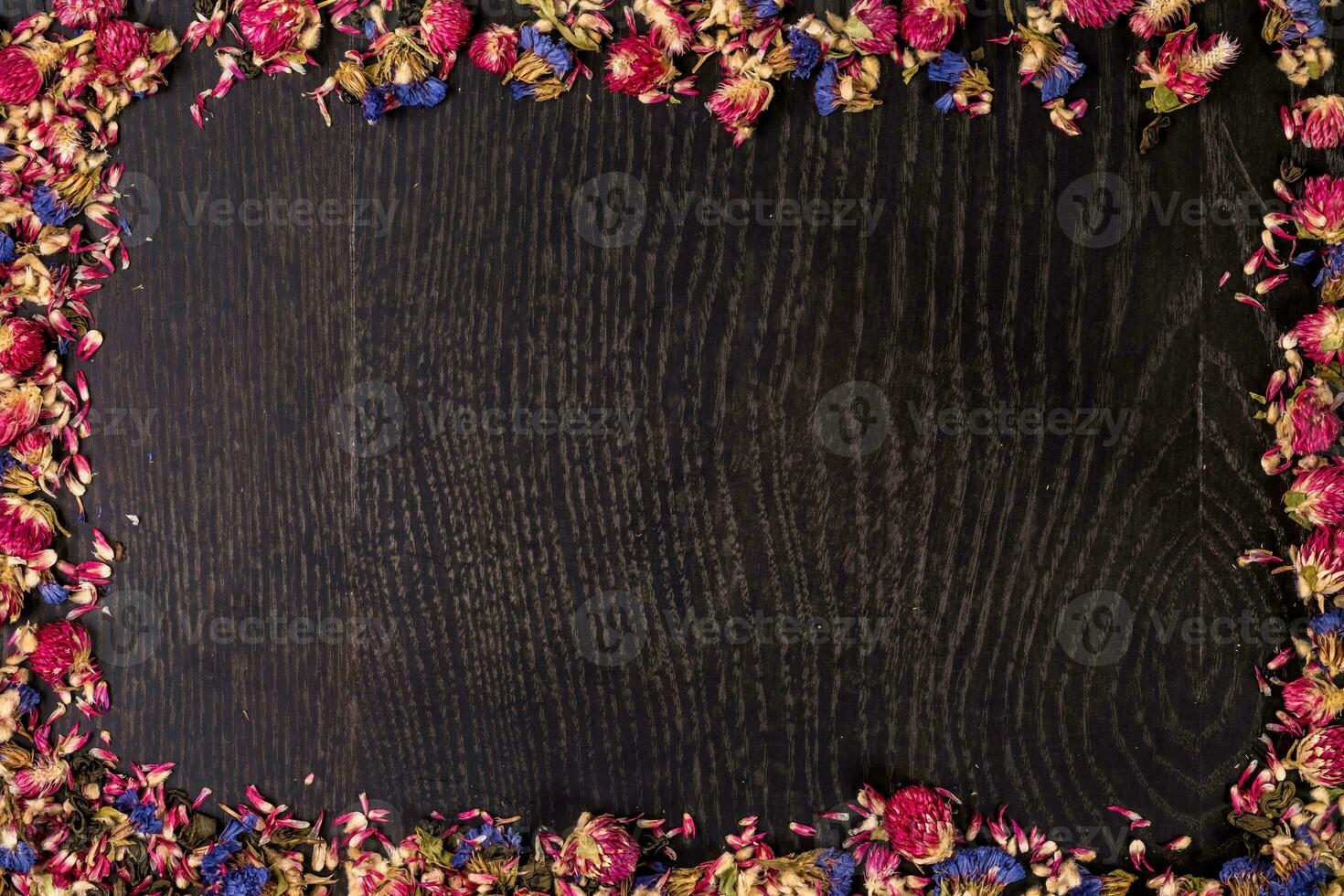 Pile of pink dried roses on black wooden background as border. photo