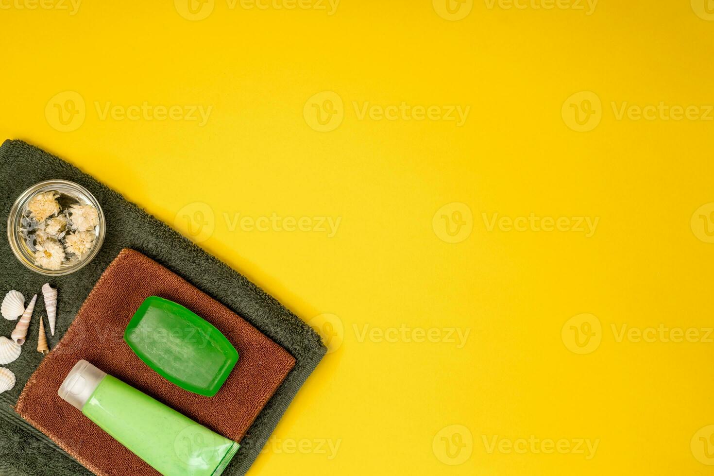 Spa or wellness setting in green colors. Bottles with essential aroma oil, towels, soap on yellow background. photo