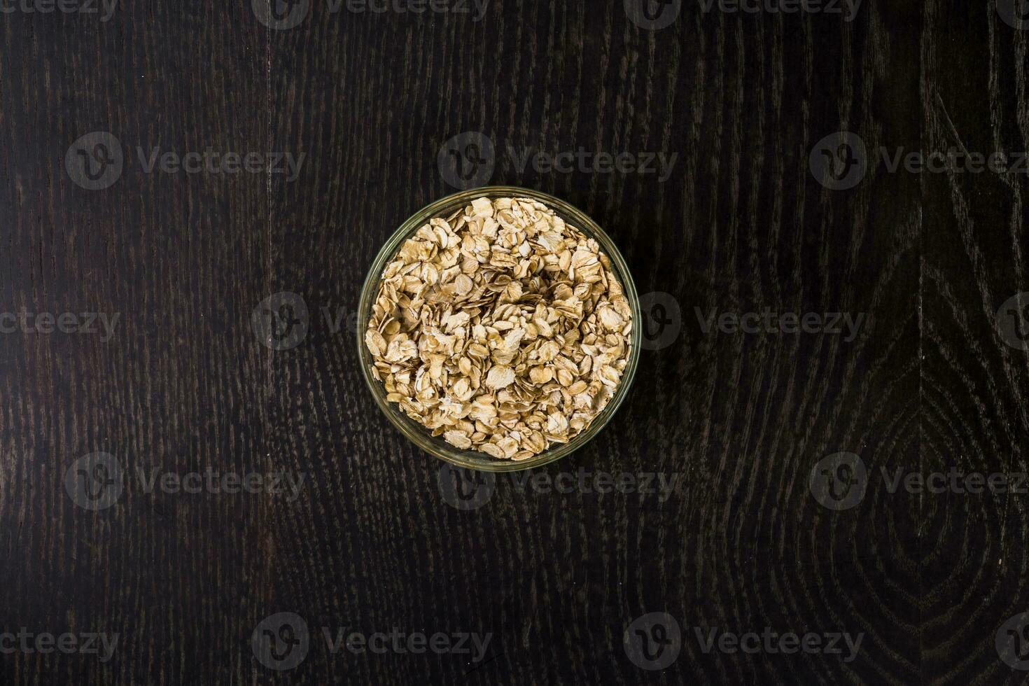 Rolled oats in a glass bowl - top view. On black background. photo