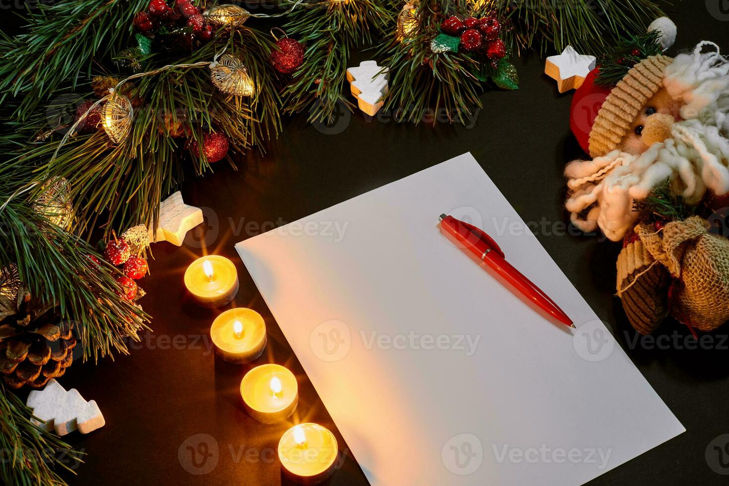 Red Christmas balls and notebook lying near green spruce branch on black background top view. Space for text photo