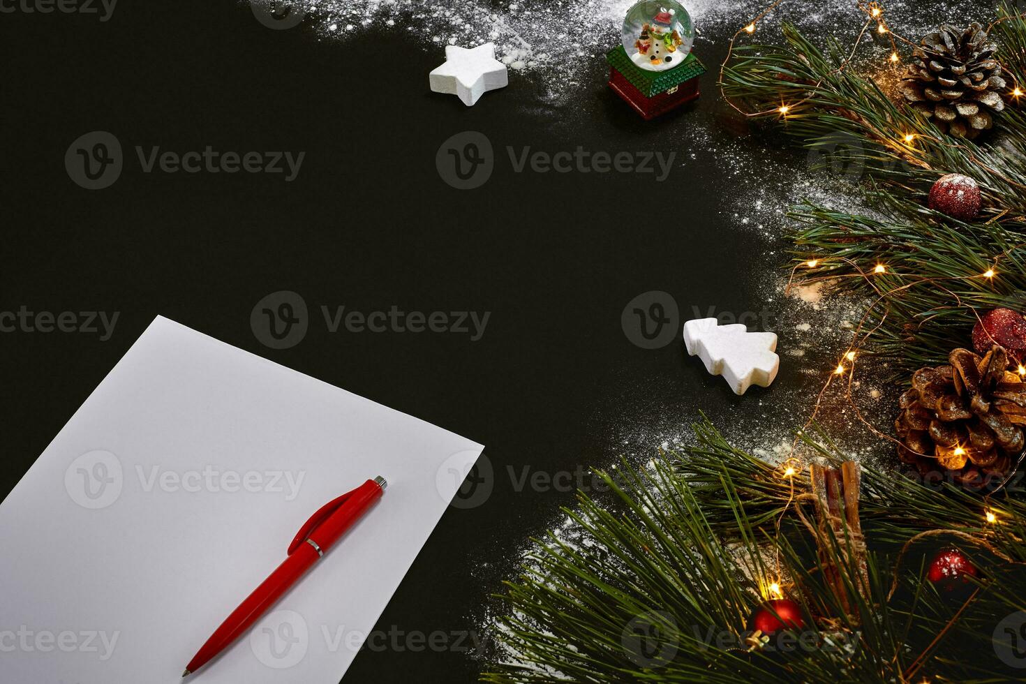 Christmas toys and notebook lying near green spruce branch on black background top view. Space for text photo