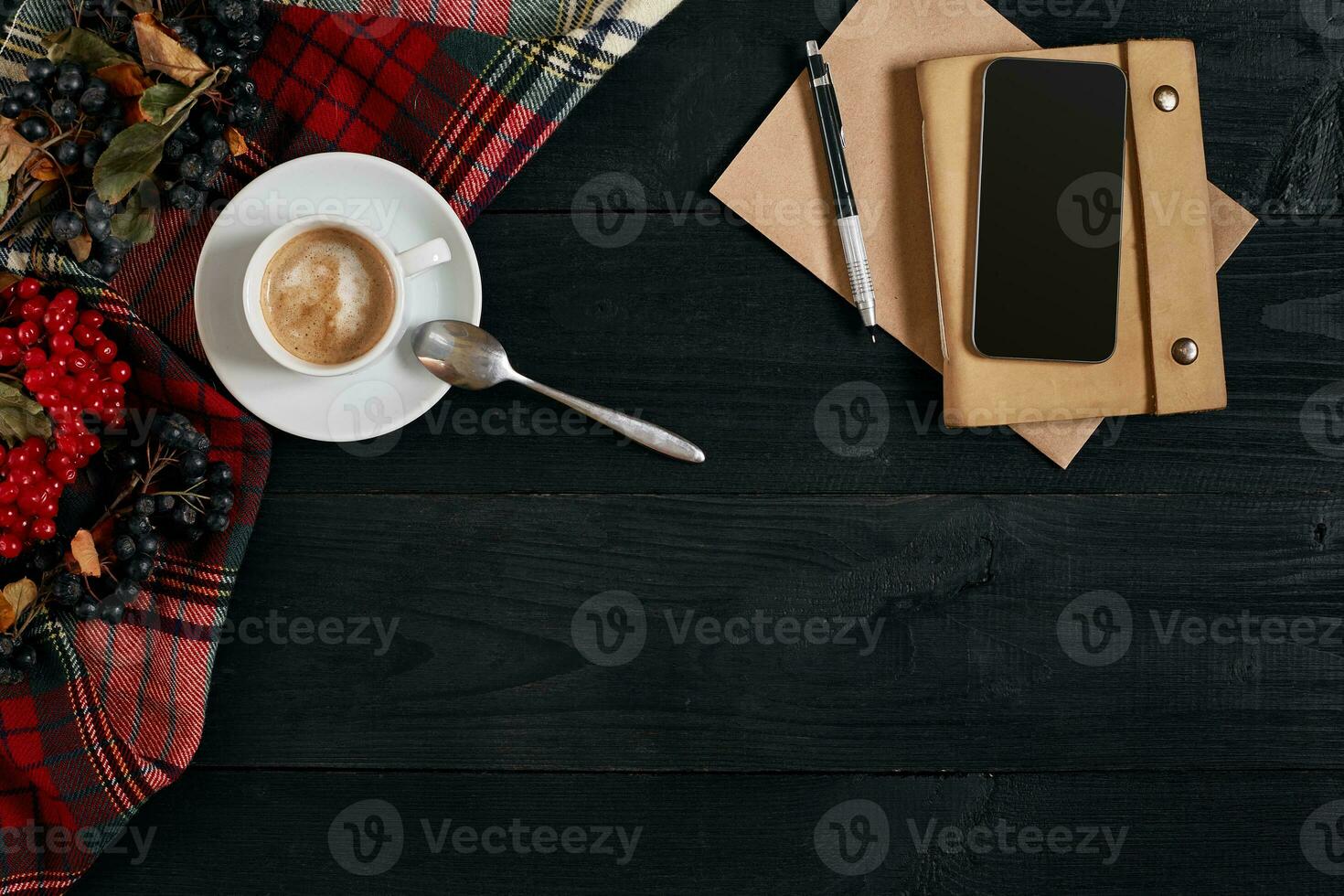 Above view of Smart phone with notebook and cup of latte coffee on black wooden background. photo