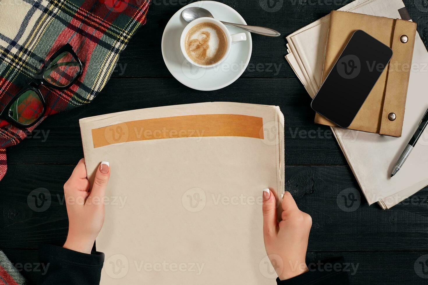 Smartphone and coffee cup, reading glasses, notebook, hands holding newspaper. photo