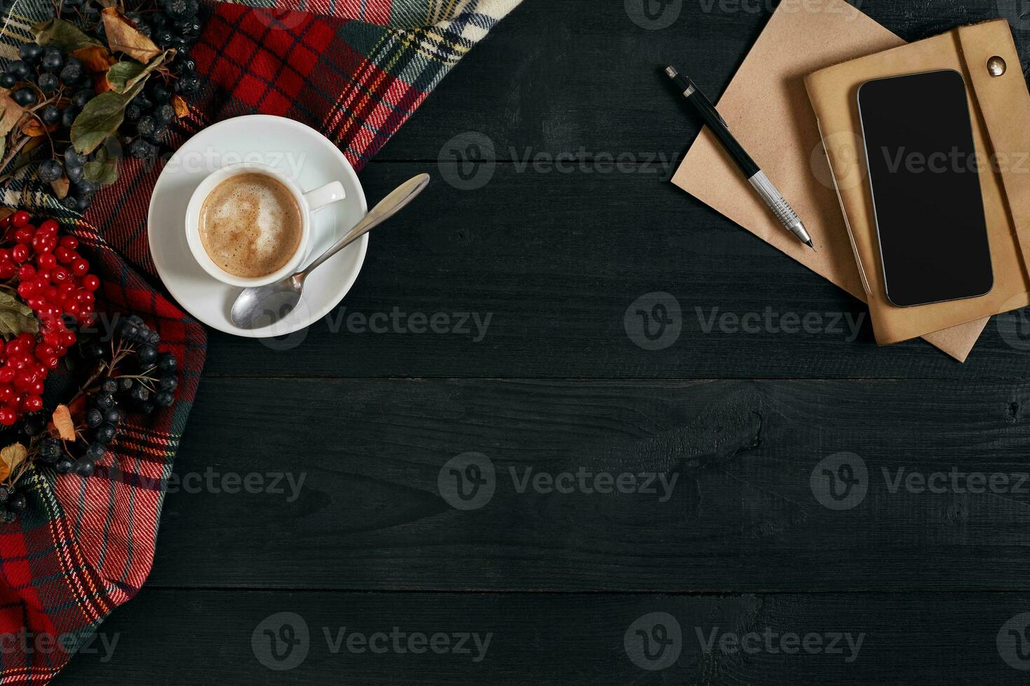 Smartphone with notebook and cup of coffee on wooden background. Cell phone with writing set with espresso photo