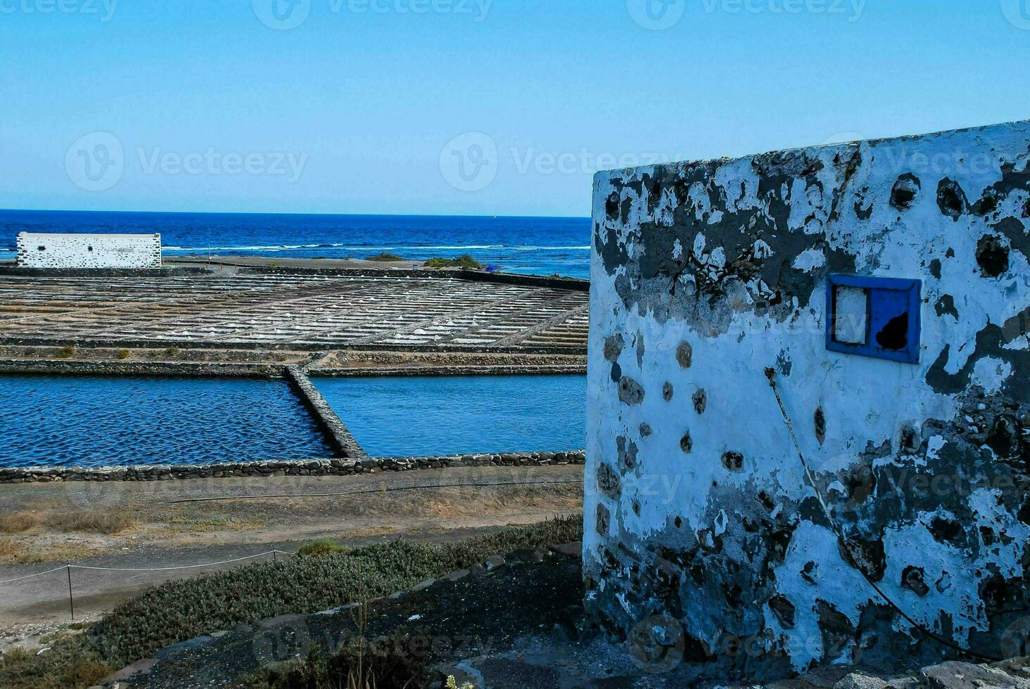 a small building with a blue window in front of the ocean photo