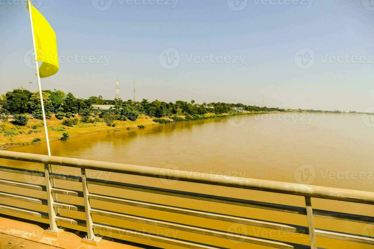 a yellow flag is hanging on a bridge over a river photo