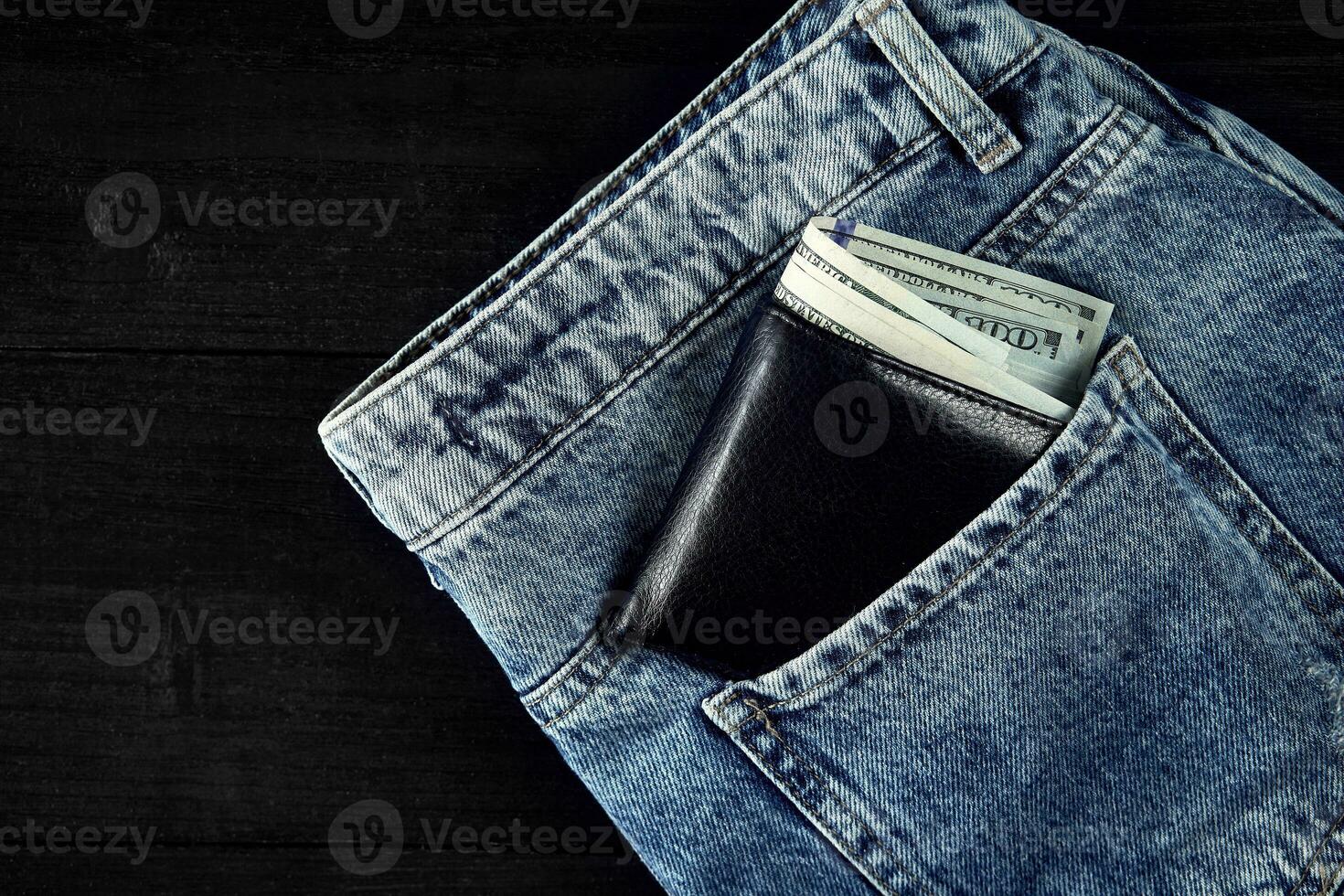 Money in pocket of blue jean on wooden background with copy space. photo