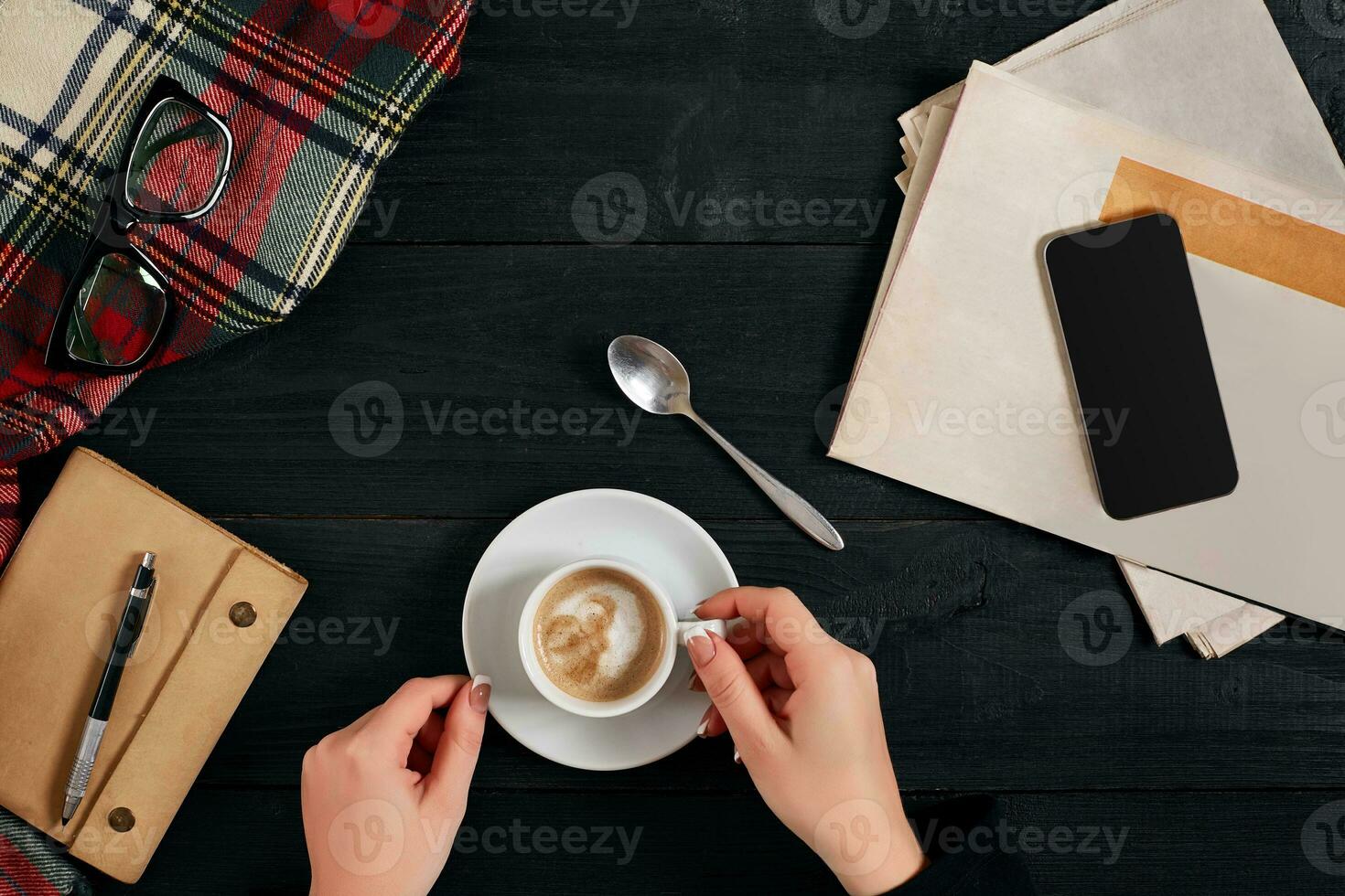 Newspaper and smartphone, reading glasses, notebook, hands holding coffee cup. photo