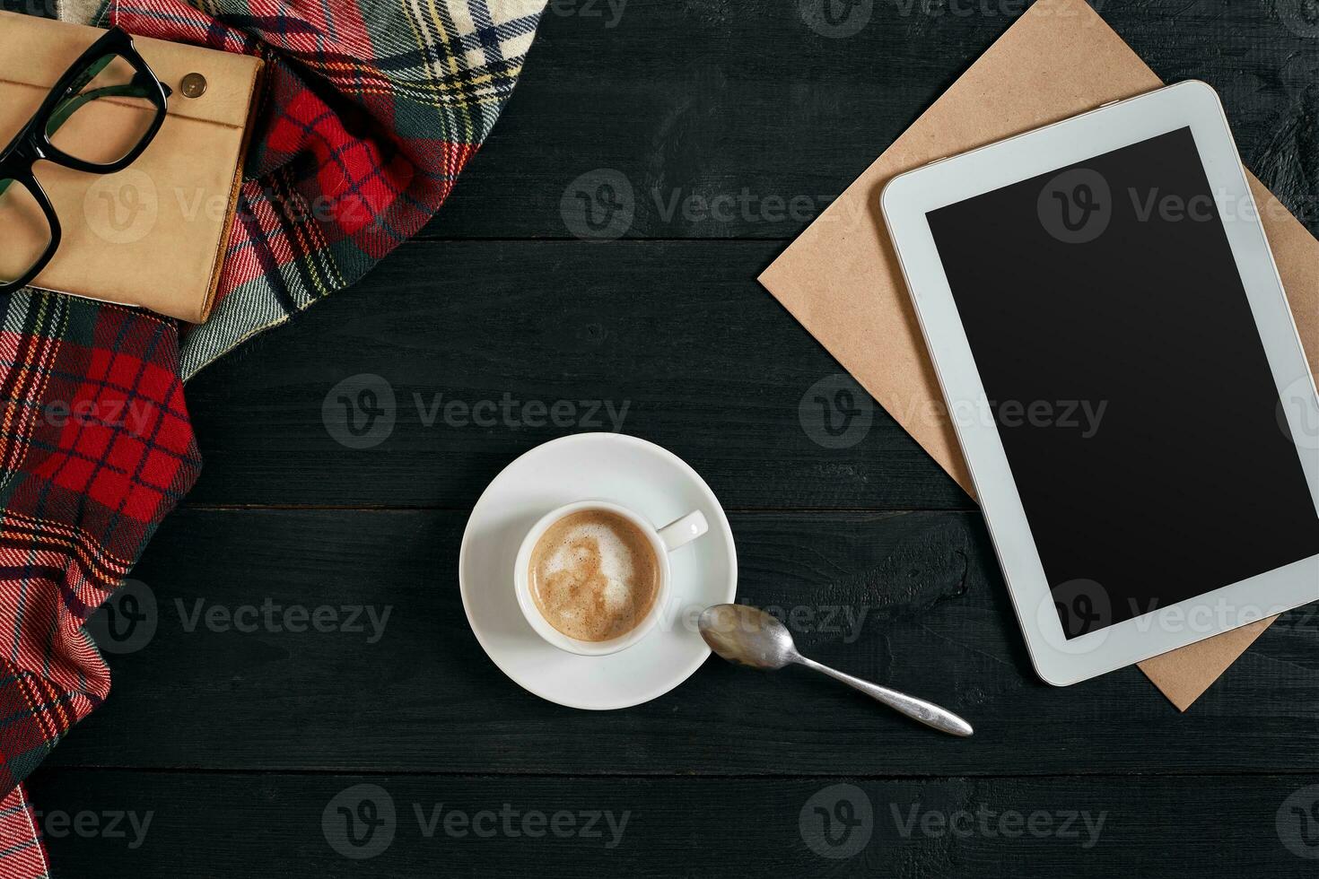 vacío tableta, un taza de café, cuaderno en el escritorio. tableta, taza caliente café en antiguo Clásico de madera tablero.arriba vista, plano laico foto