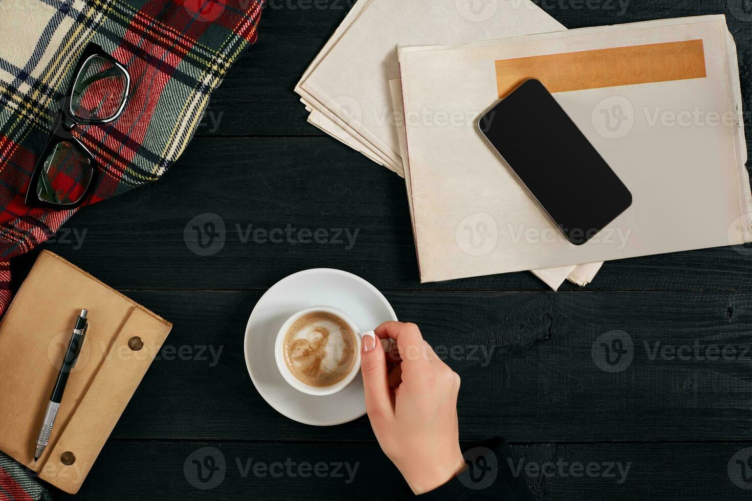 Newspaper and smartphone, reading glasses, notebook, hands holding coffee cup. photo