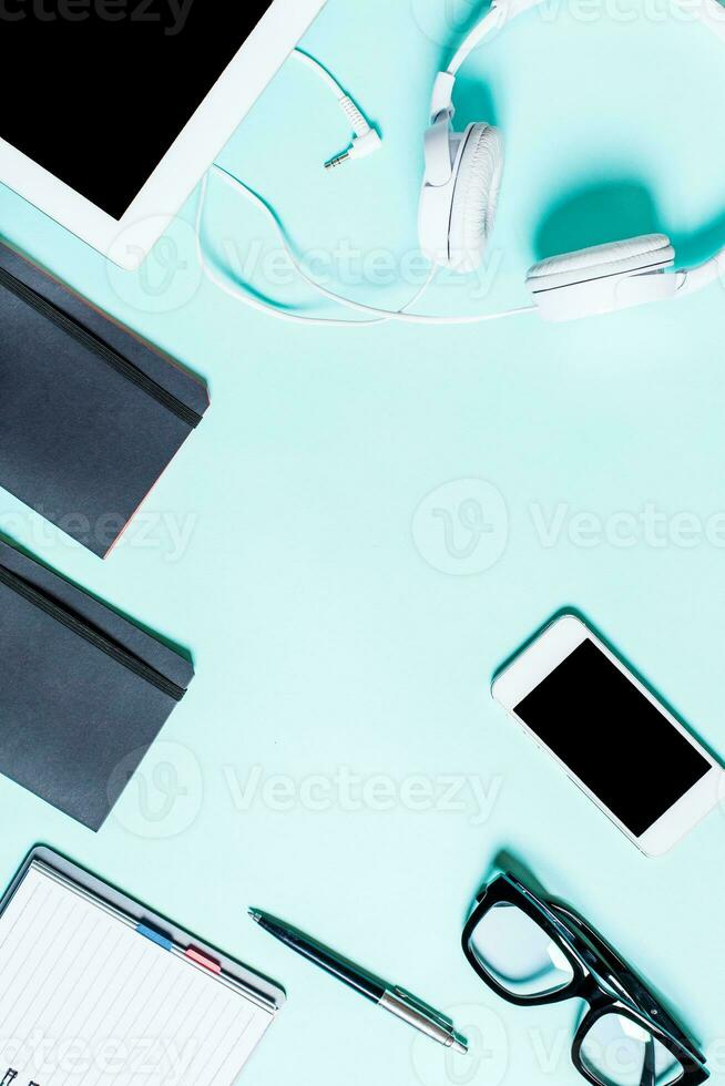 Working place with tablet, smartphone and glasses on a turquoise background photo