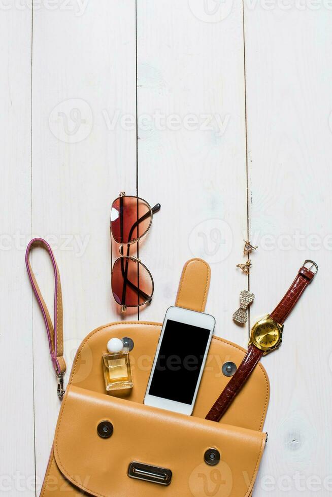 Women's accessories fell out of the beige handbag on white background. photo