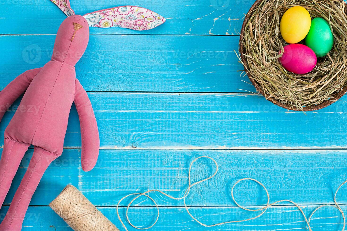 Easter eggs in nest and rabbit on blue rustic wooden planks photo
