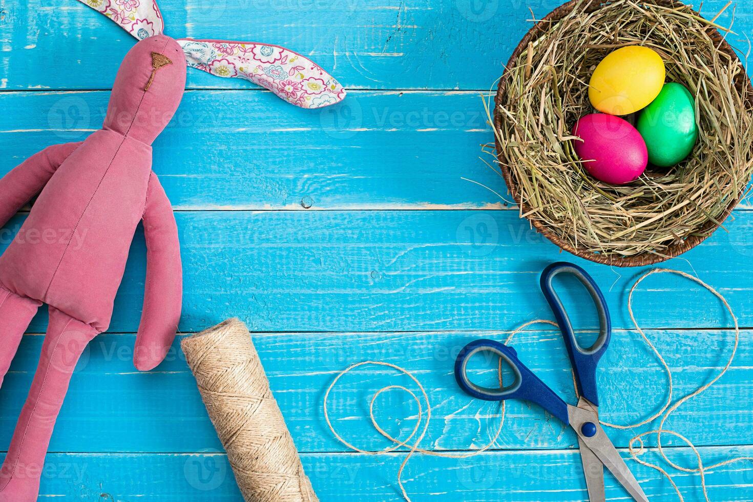 Colorful easter egg in nest on blue wood board. photo