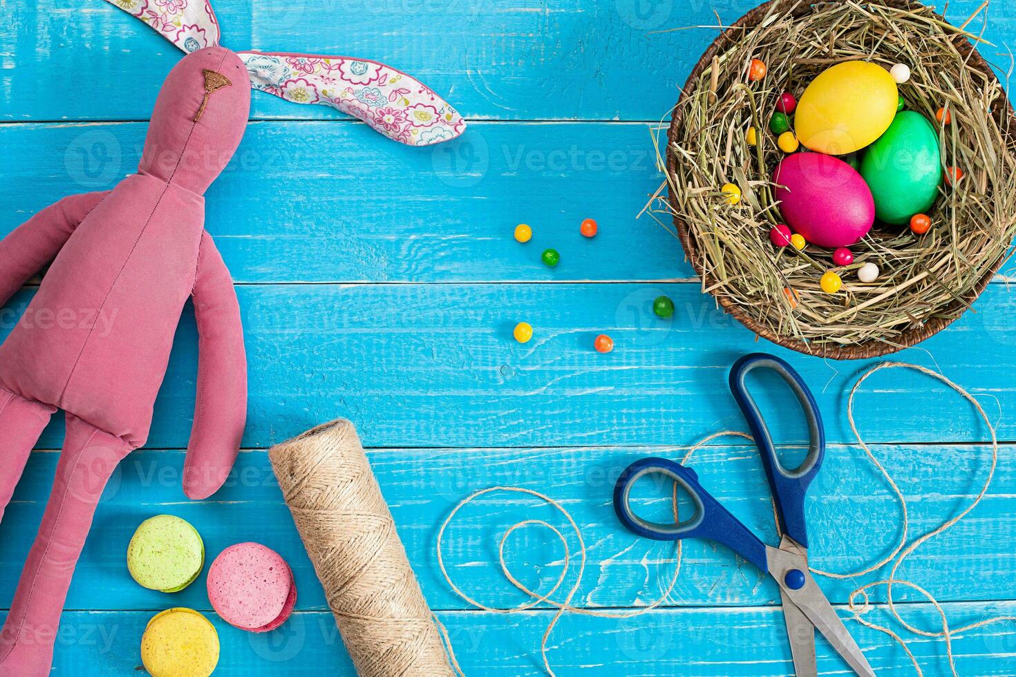 Easter eggs in nest and rabbit on blue rustic wooden planks photo