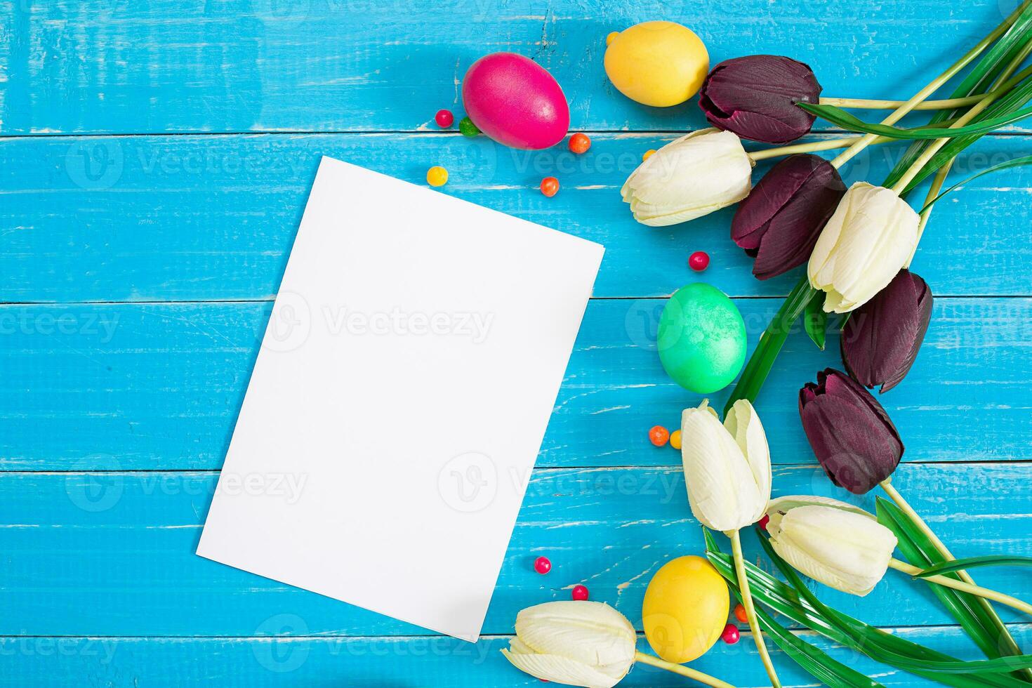 Colorful easter eggs and tulips on blue rustic wooden background photo