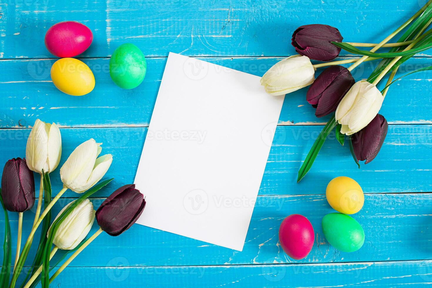 Colorful easter eggs and tulips on blue rustic wooden background photo