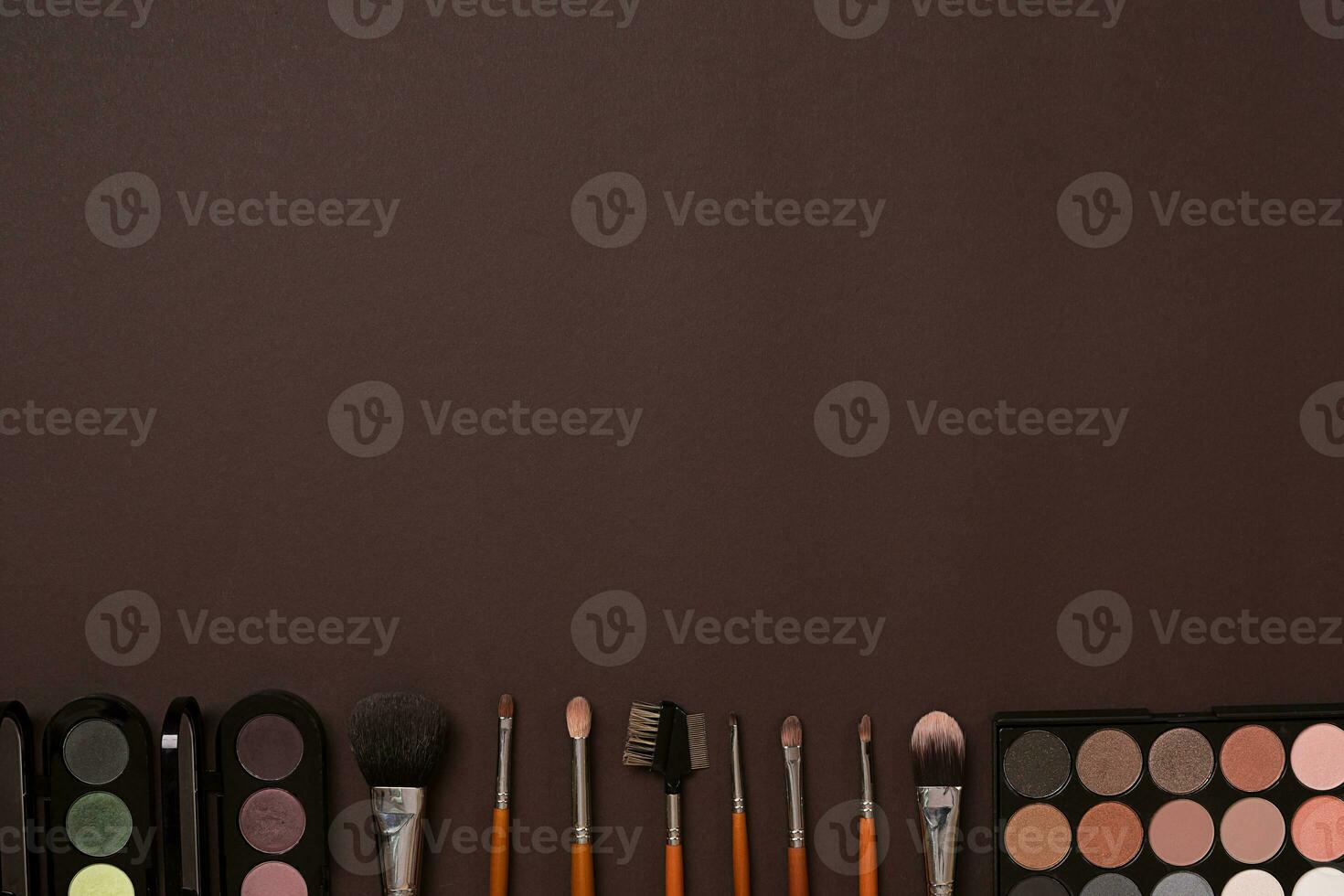 Various cosmetics and brushes on brown background photo