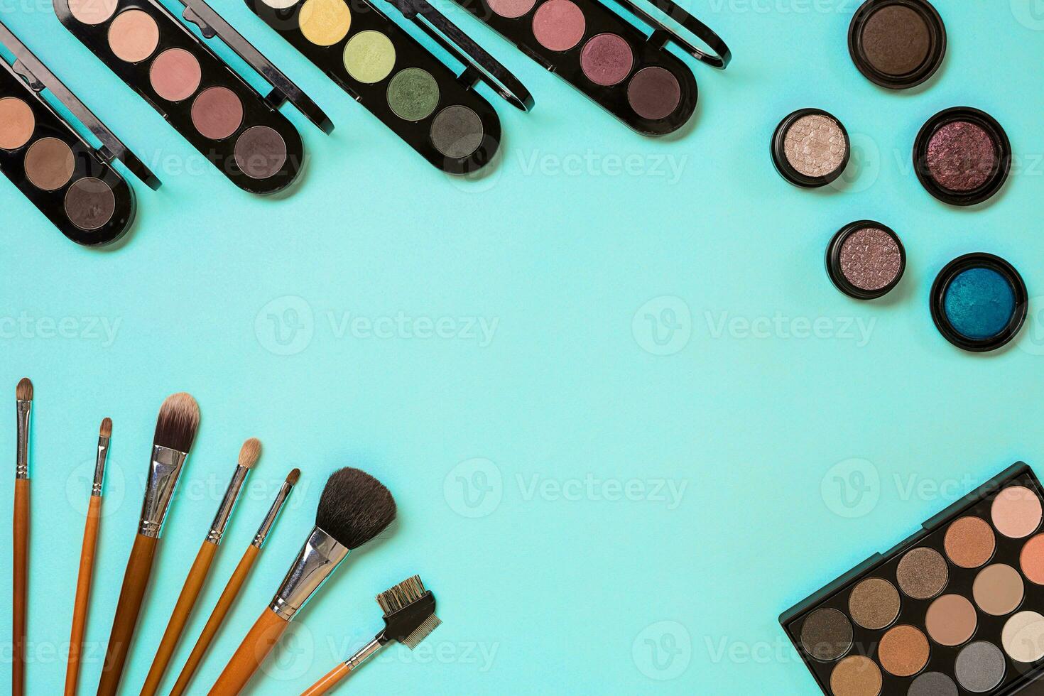 Make up essentials. Set of professional make up brushes, creams and shadows in jars on blue background. photo