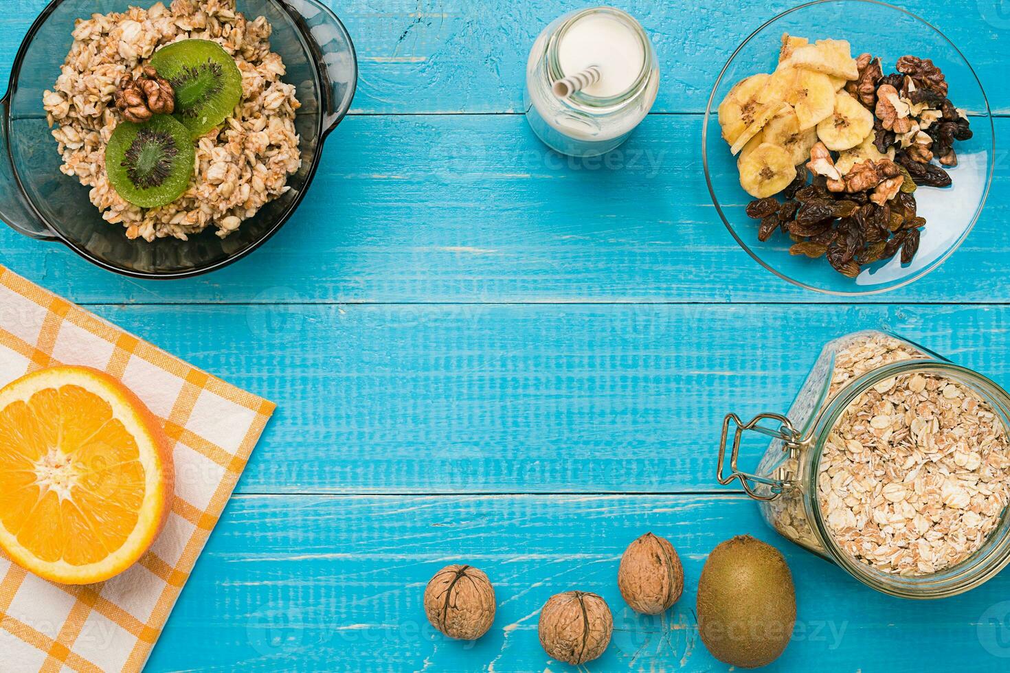 Bowl of fresh oatmeal porridge with kiwi and nuts on teal rustic table photo