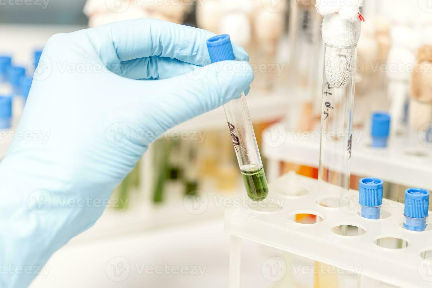 Scientist fingers holding a glass test tube in a research lab photo