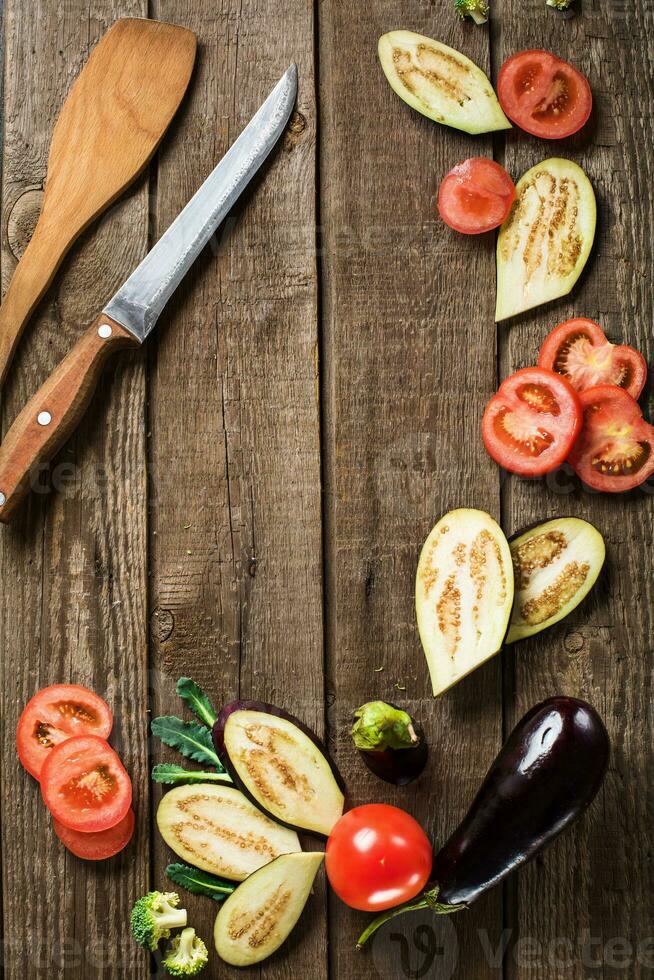 sliced eggplant, tomato, broccoli on slate and wooden counter top background photo