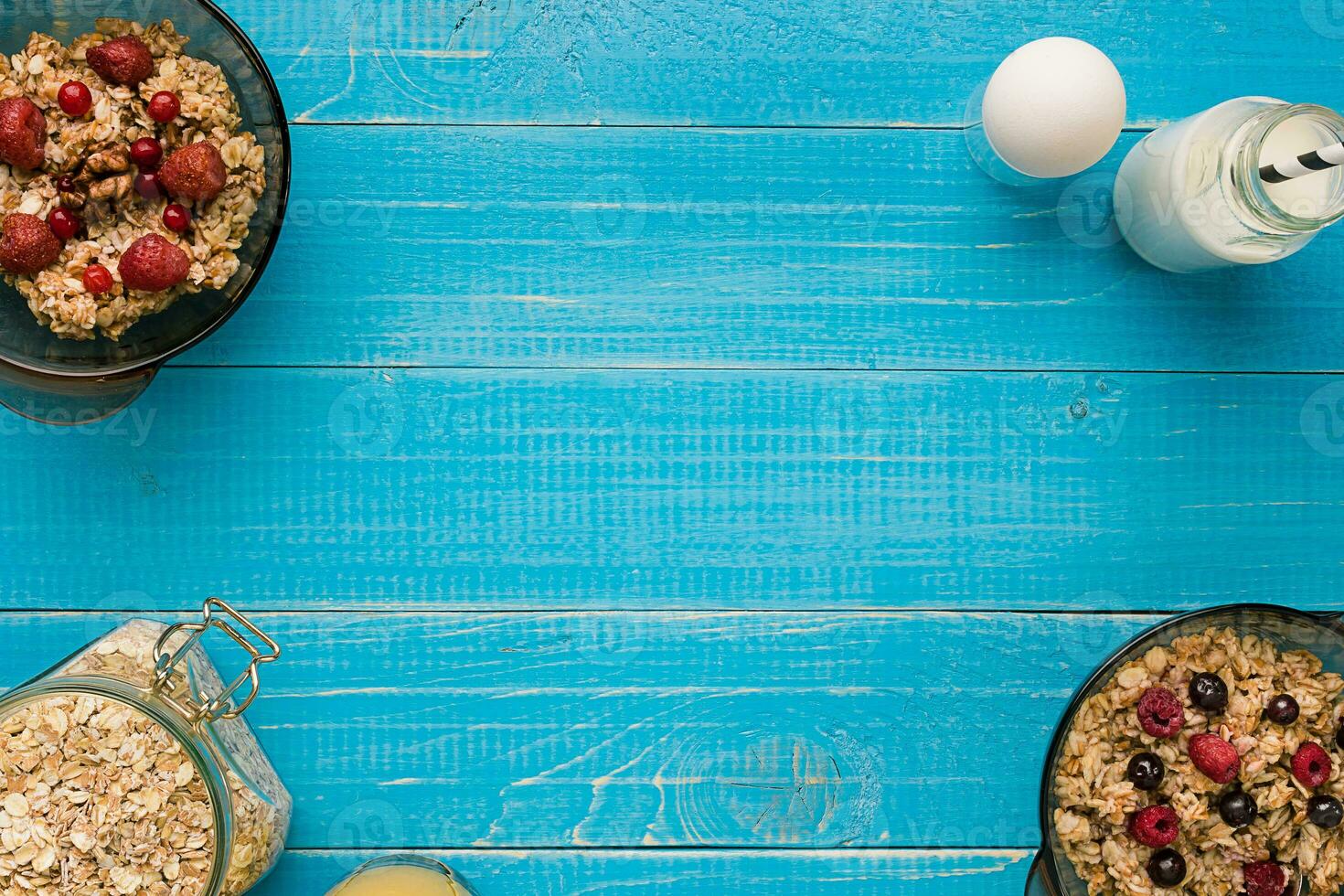 oat flakes with milk and berries bowl with spoon on blue wooden background, top view photo