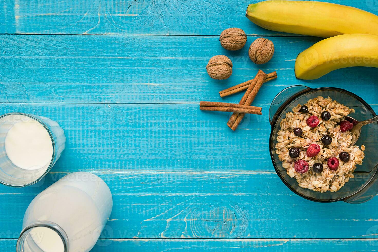 oatmeal porridge with banana, kiwi fruit, nuts and honey in a bowl with egg for healthy breakfast on rustic wooden background. top view photo