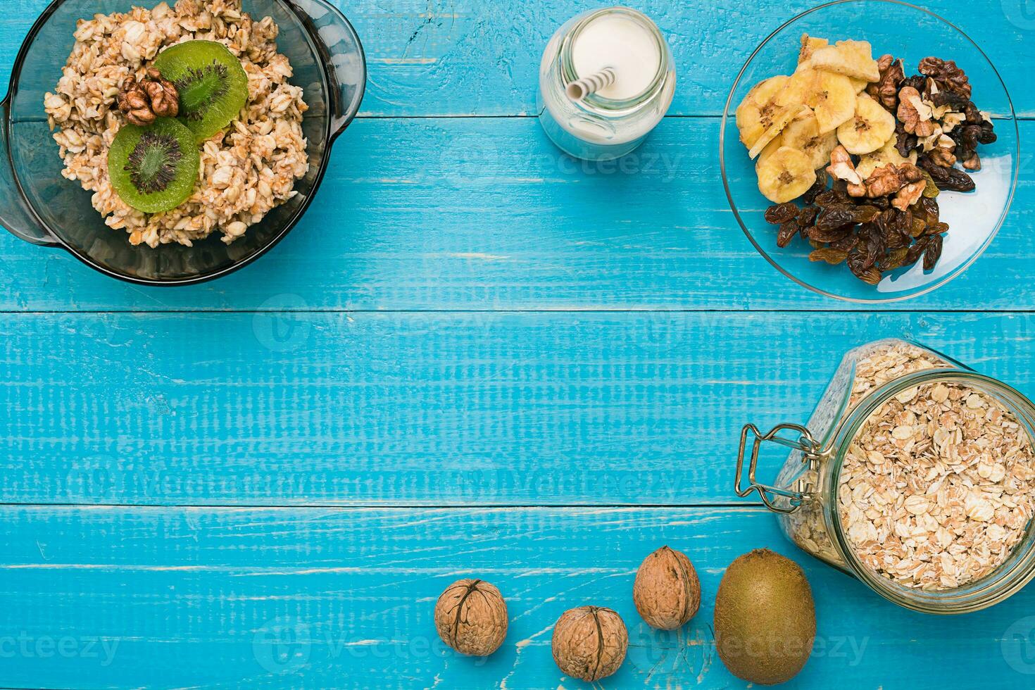 Bowl of fresh oatmeal porridge with kiwi and nuts on teal rustic table photo