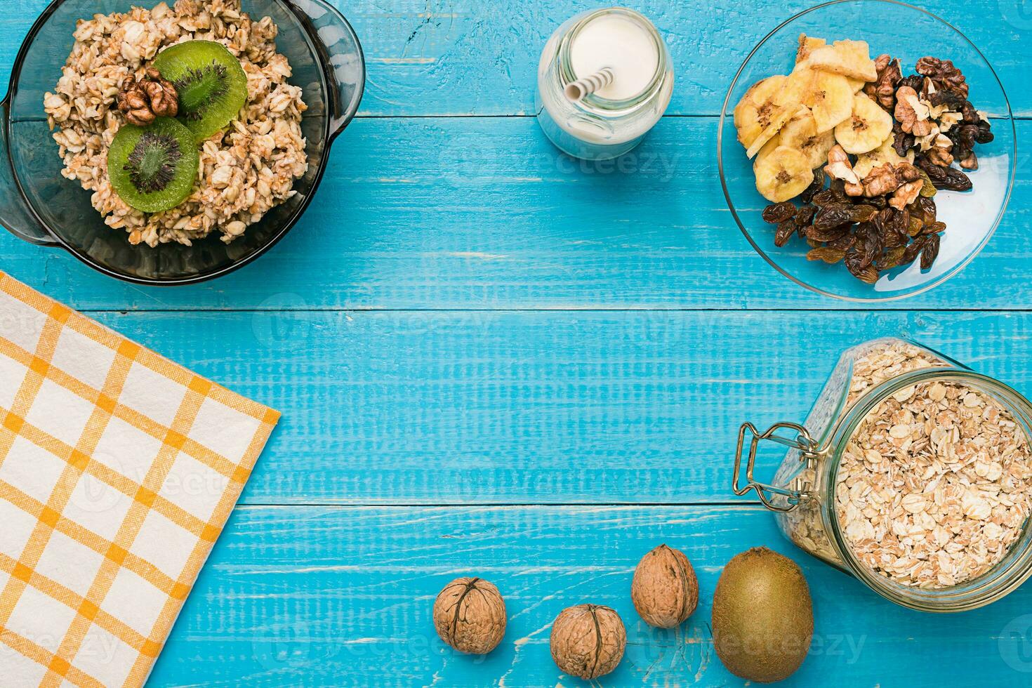 Bowl of fresh oatmeal porridge with kiwi and nuts on teal rustic table photo