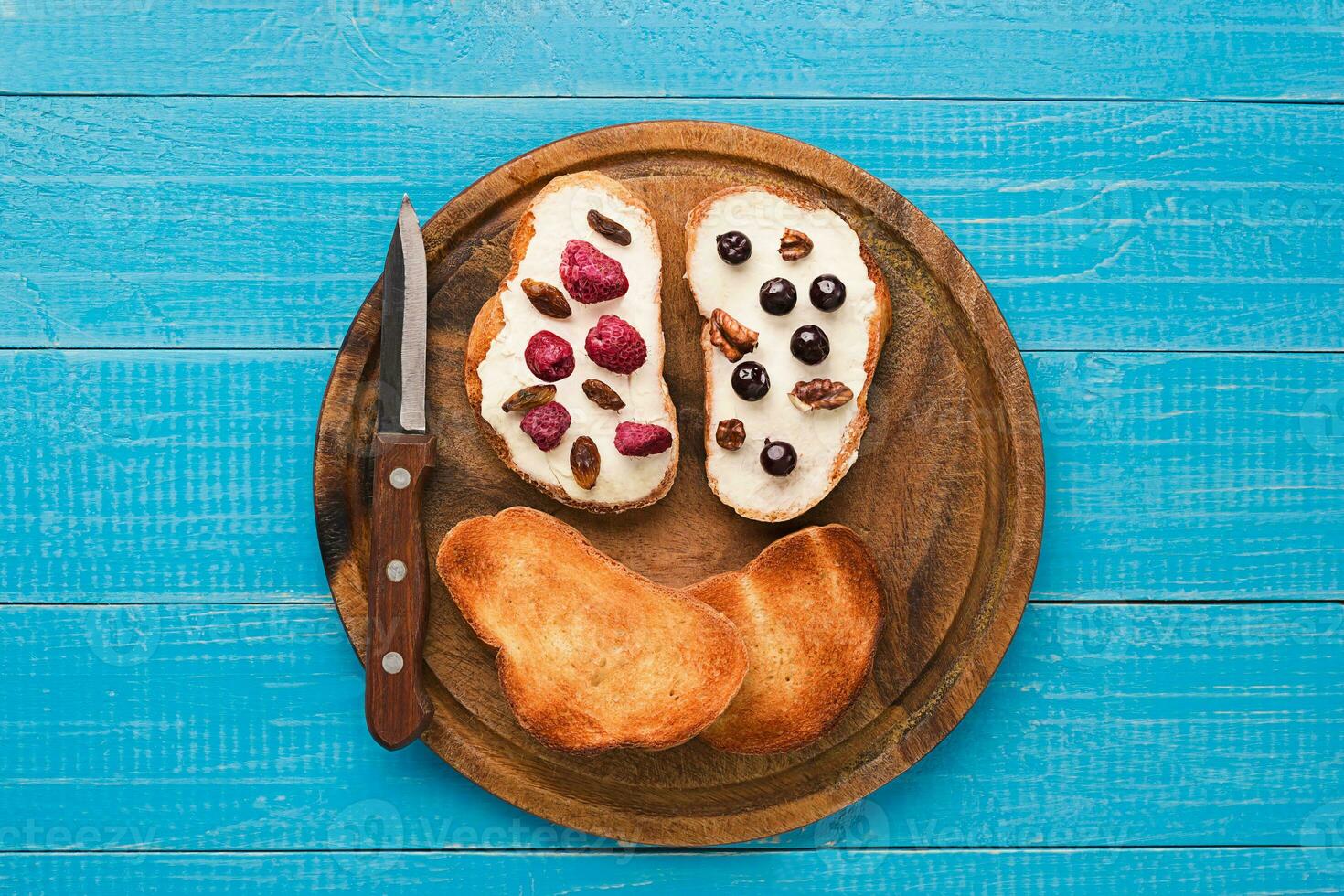 Butter sandwiches on healthy wholewheat bread topped with fresh raspberries, currants and raisins. Top view photo