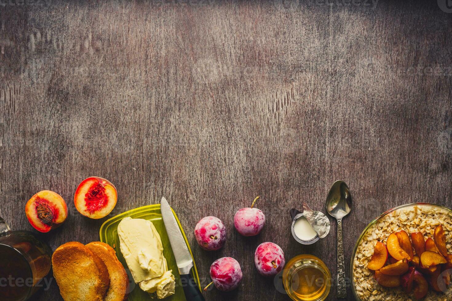 Healthy breakfast with oatmeal in a glass bowl and fruit on table. Toned photo