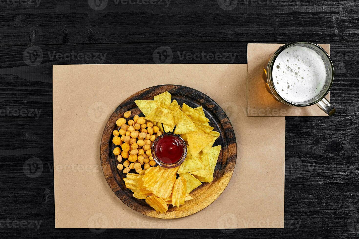 Lager beer and snacks on black wooden table. Nuts, chips. Top view with copyspace photo